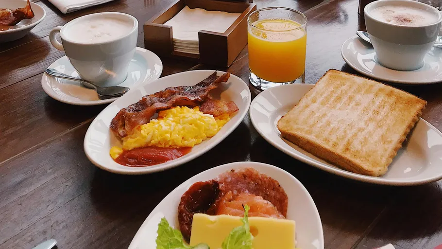 Frühstück mit Speck, Eiern, Toast, Saft, Kaffee.