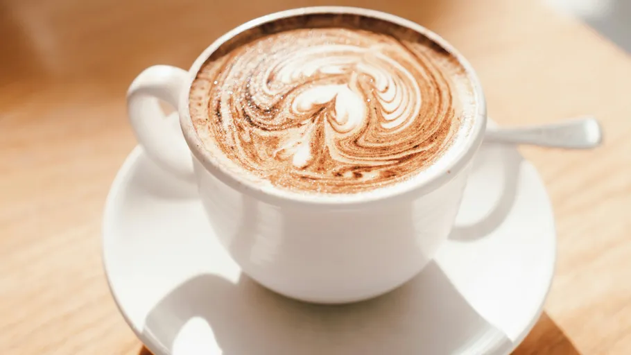 Tasse Cappuccino mit Latte Art auf Tisch.