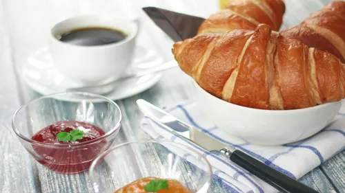 Croissants und Kaffee auf Frühstückstisch.