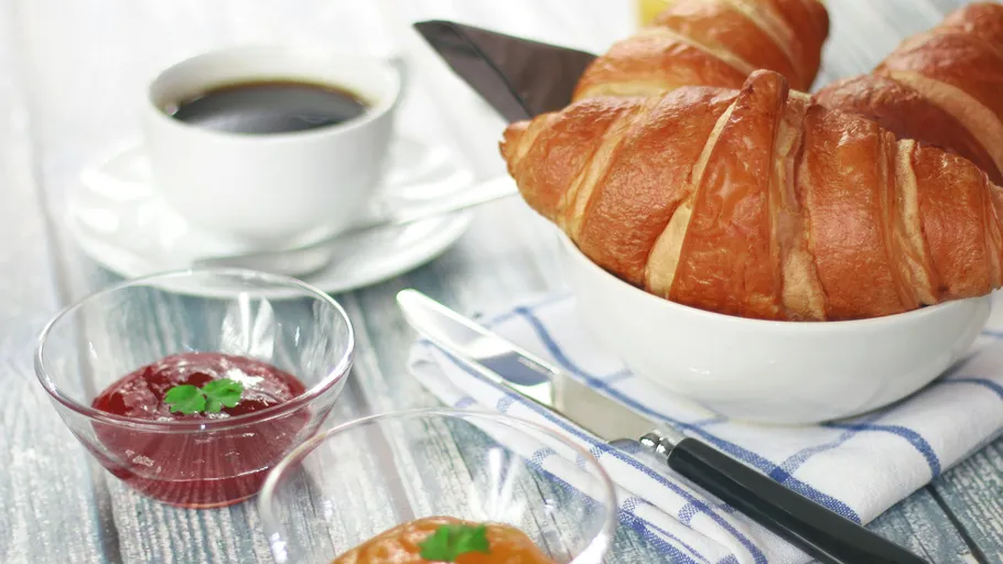 Croissants und Kaffee auf Frühstückstisch.