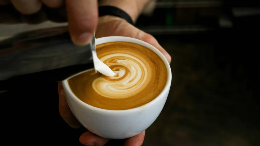 Barista gießt Latte Art in Kaffeetasse.