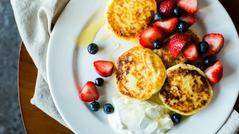 Pfannkuchen mit Beeren und Sahne auf Teller.