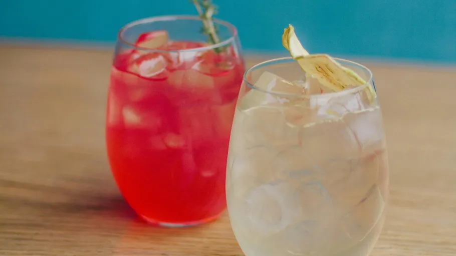 Zwei Cocktails mit Garnitur auf Holztisch.