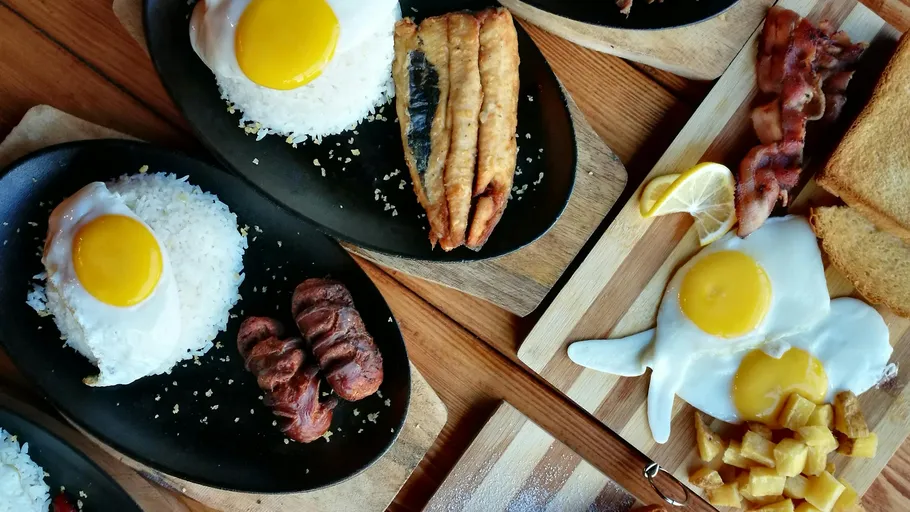 Frühstücksteller mit Eiern, Reis, Fleisch und Toast.