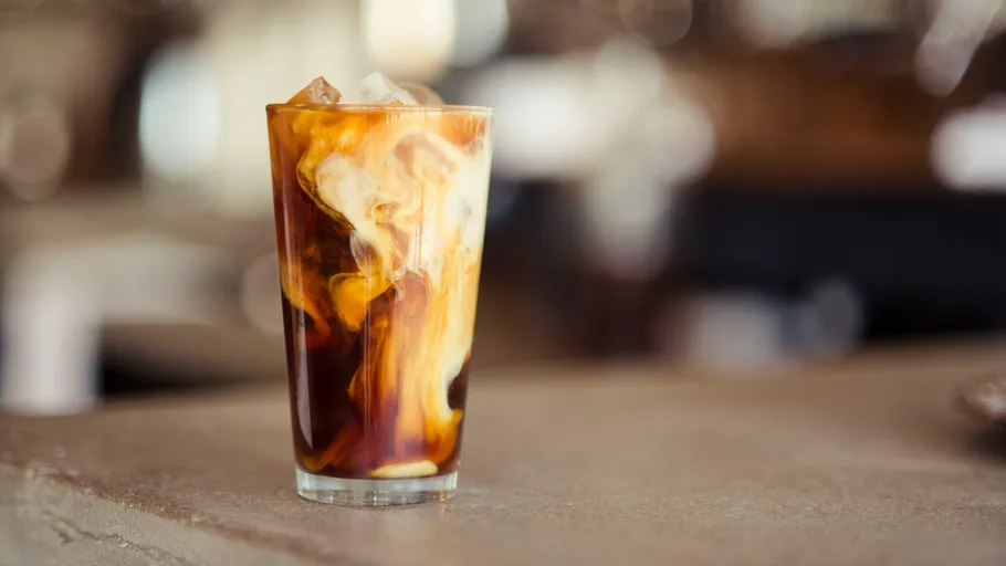 Eiskaffee mit Milch im Glas wirbelnd.