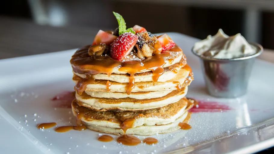 Gestapelte Pfannkuchen mit Obst und Karamellsauce.