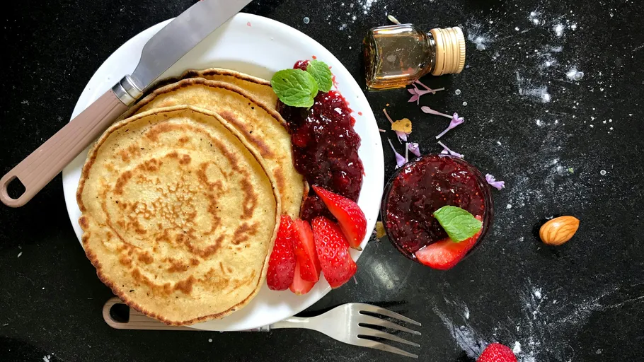 Pfannkuchen mit Erdbeeren und Marmelade auf Teller.