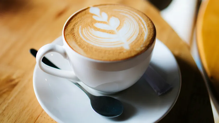Kaffeetasse mit Latte Art auf Tisch.