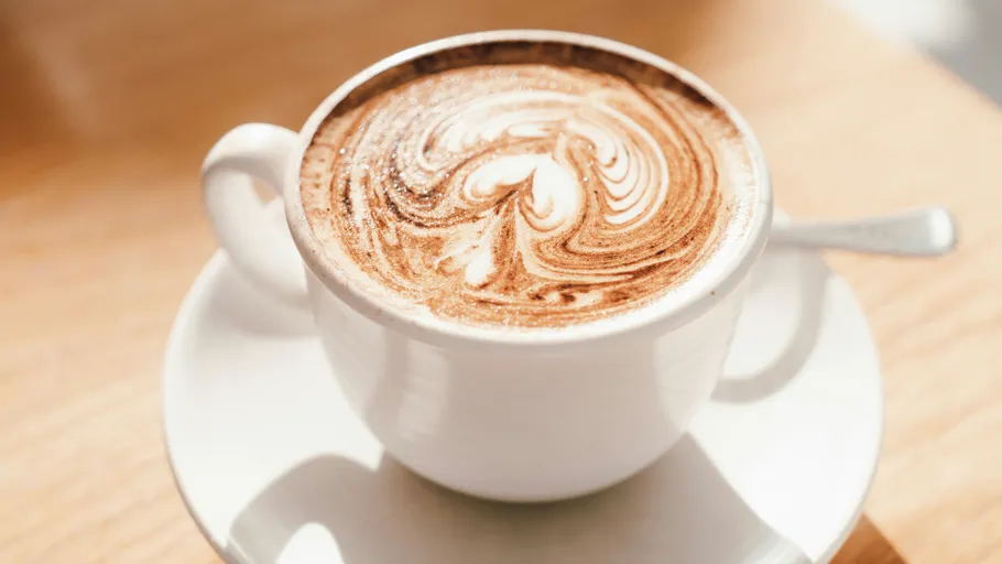 Tasse Cappuccino mit Latte Art auf Tisch.