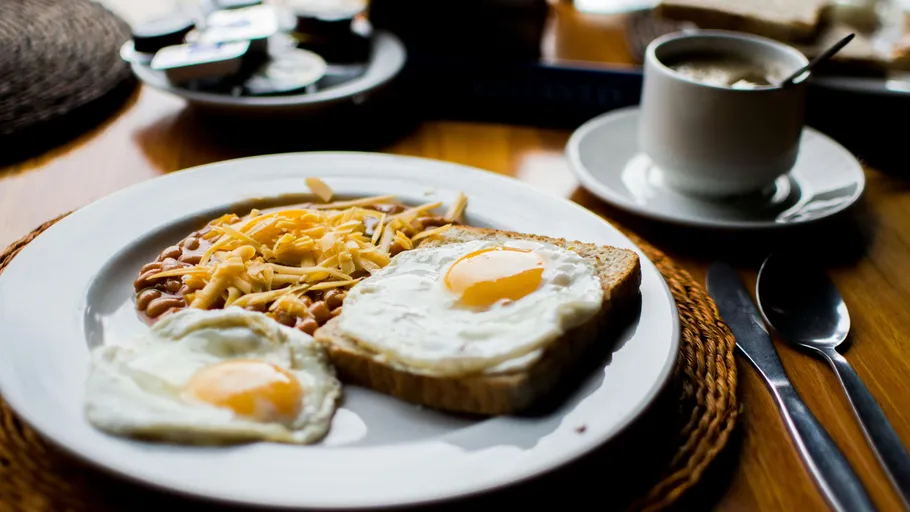 Plate with eggs, beans, and toast; coffee beside.