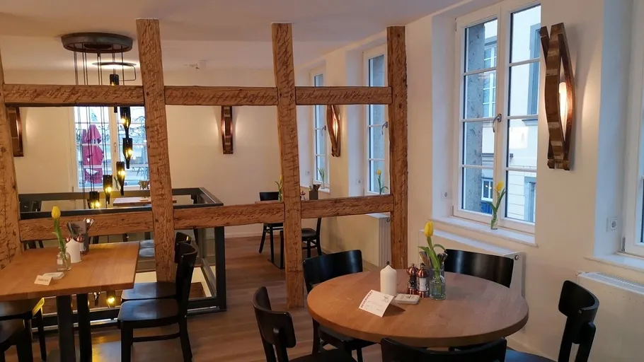 Gemütliches Café mit Holztischen und warmer Beleuchtung.