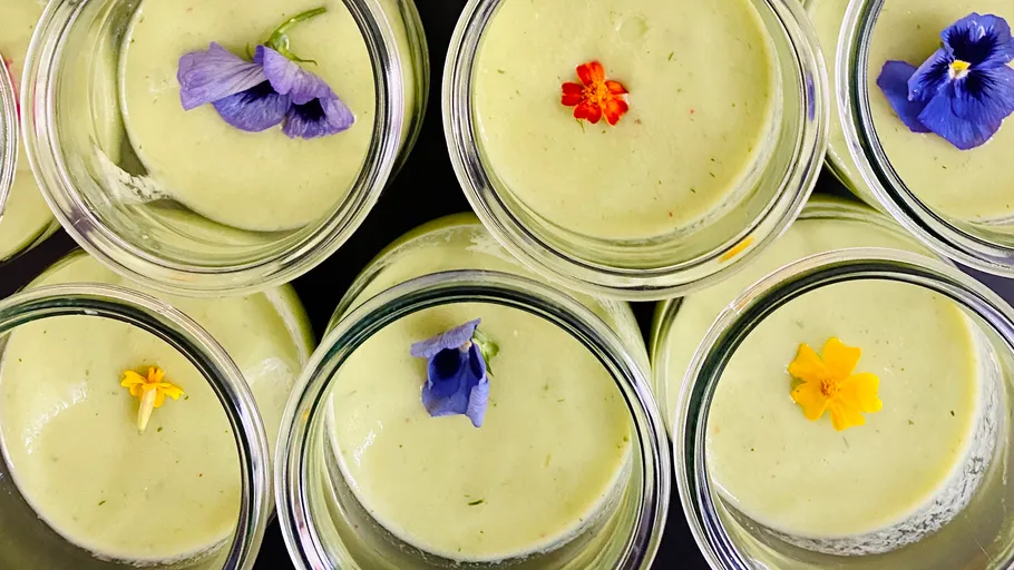 Grüne Desserts in Gläsern mit bunten Blumen.