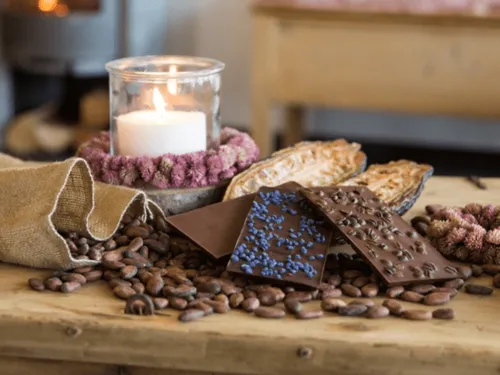 Chocolate bars lie on coffee beans, next to a candle.