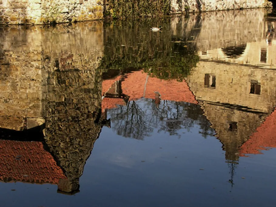 Spiegelung eines alten Steingebäudes im Wasser.