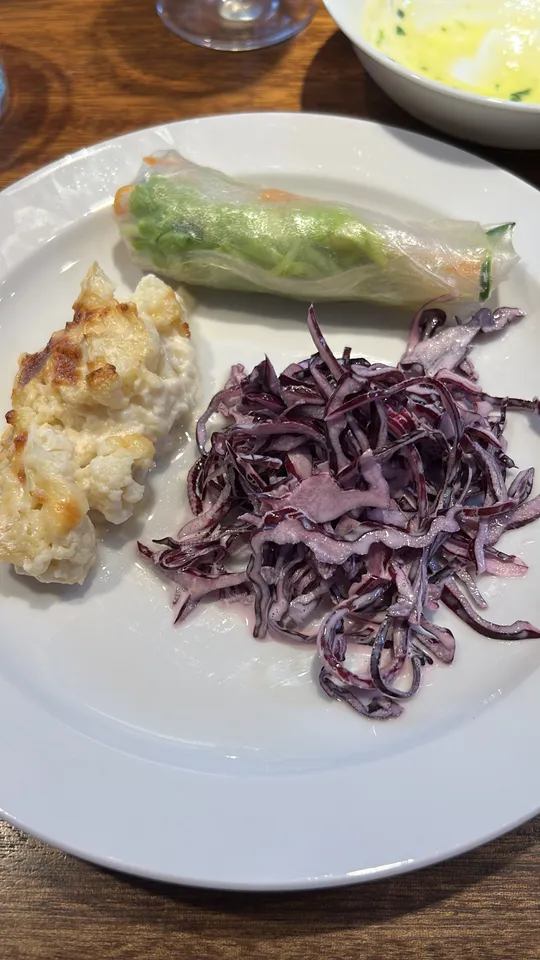 Teller mit Krautsalat, Frühlingsrolle und Gratin.