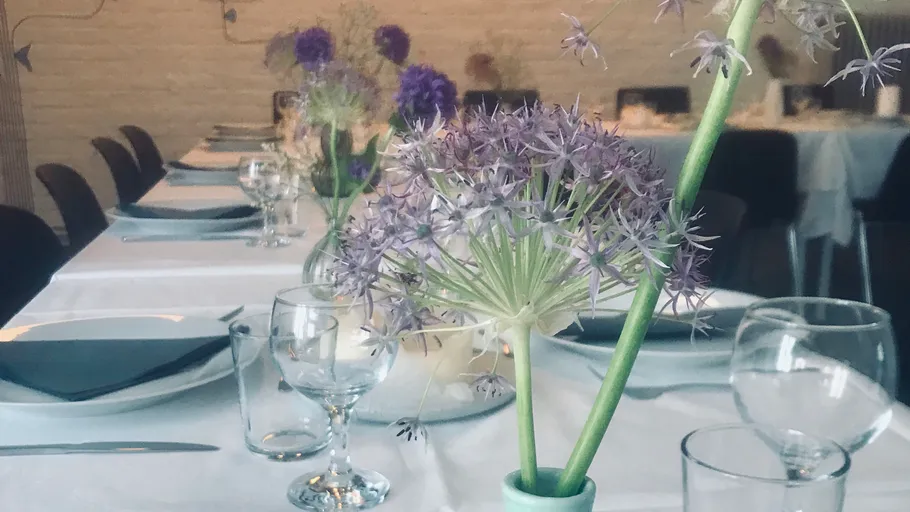 Lila Blumen auf elegant gedecktem Esstisch.