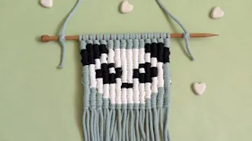 Makramee-Panda auf grünem Hintergrund, Herzakzente.