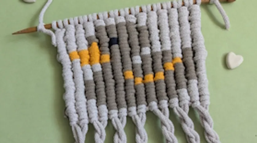 Gestricktes Entenmotiv auf grünem Hintergrund.