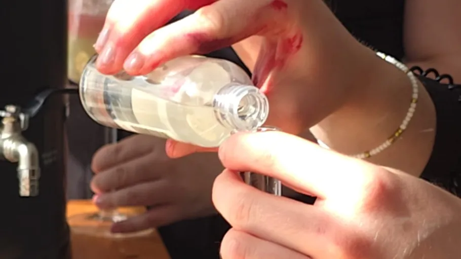 Person füllt eine kleine Flasche mit Flüssigkeit.
