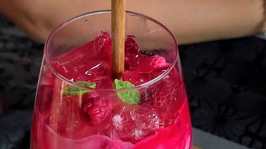 Pink cocktail with raspberries and mint garnish.