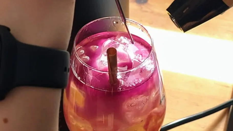 Buntes Getränk mit Strohhalm auf Tisch.