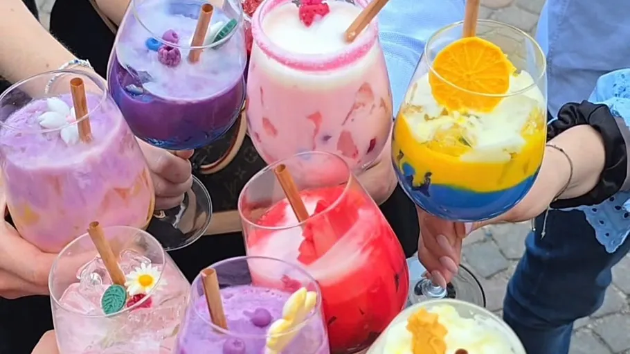 Colorful drinks held by people outdoors.
