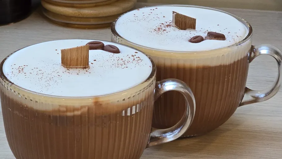Zwei Cappuccinos mit Schaum und Schokoladentopping, innen.