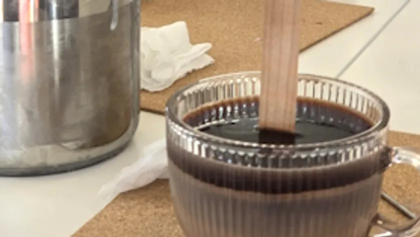 Glasbecher mit dunkler Flüssigkeit auf Tisch.