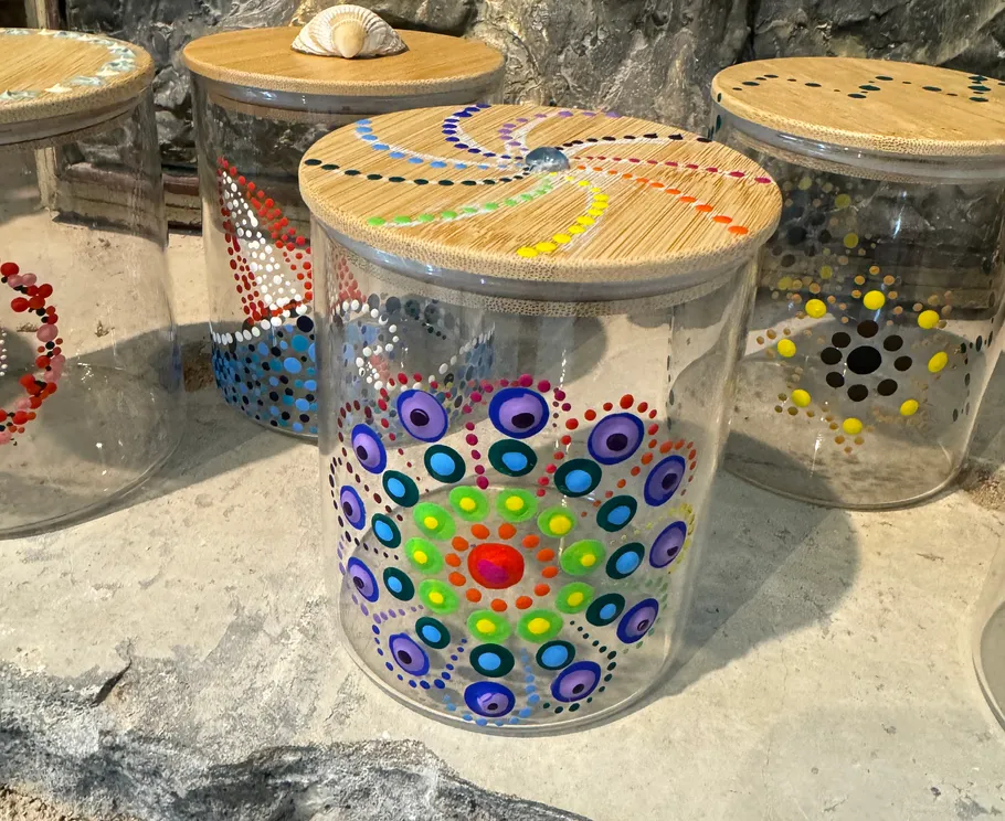 Dekorierte Glasbehälter mit Holzdeckeln auf Steinoberfläche.