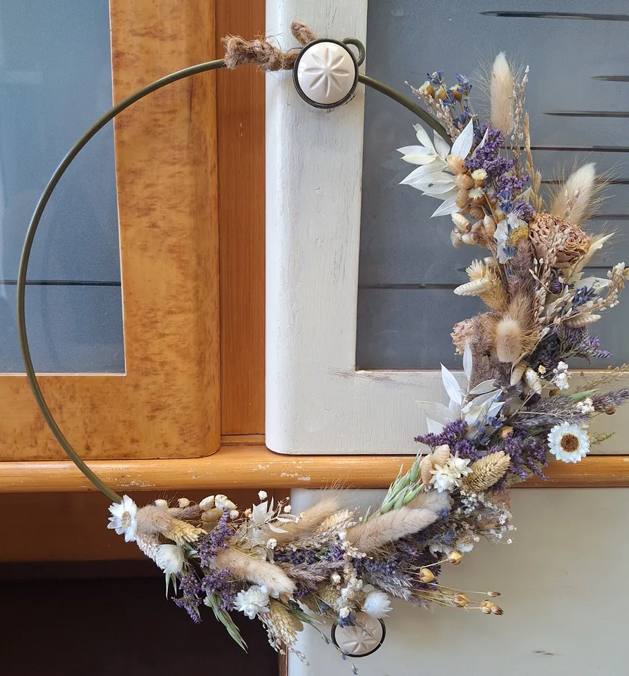 Floral wreath with dried flowers on shelf.