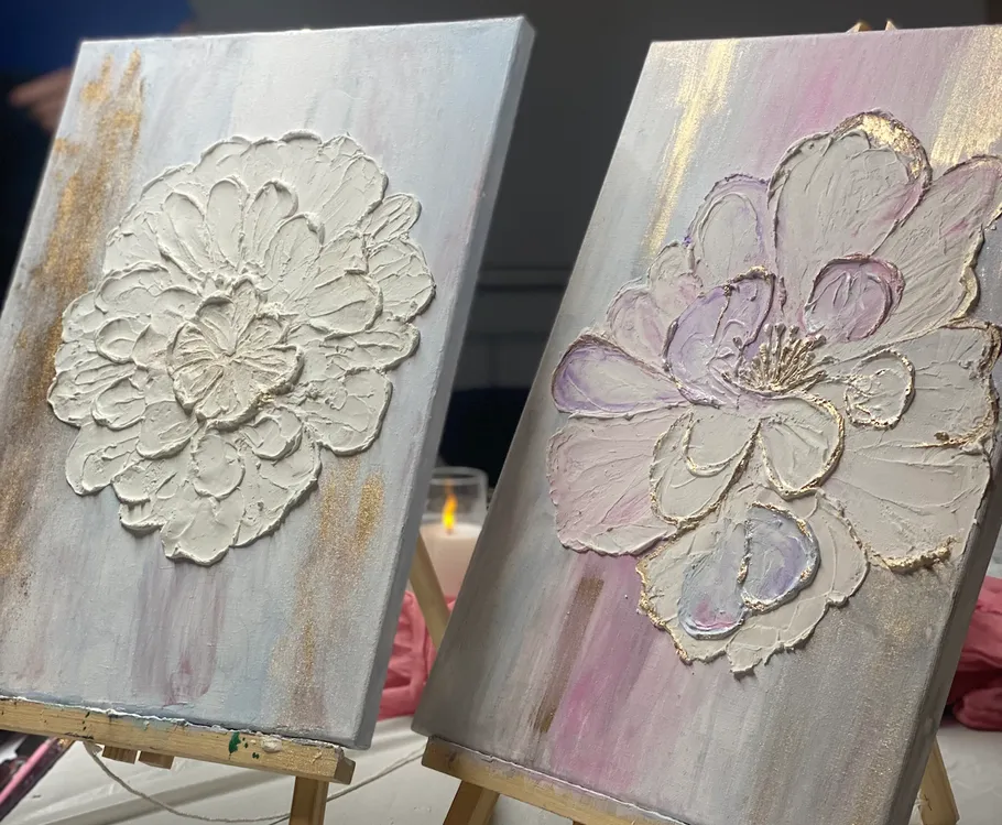 Two floral textured paintings on easels indoors.