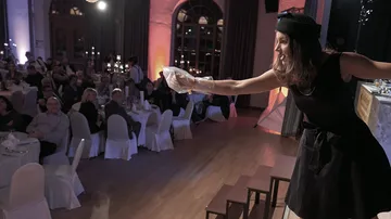 Woman in black dress performing on stage at event.