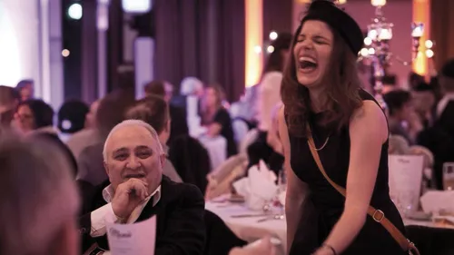 Frau lacht fröhlich bei einem Dinner-Event.