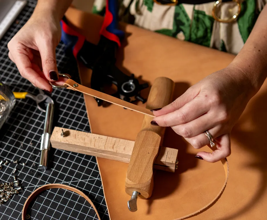 Craftsperson working with leather on table.