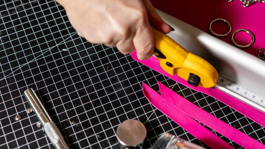 Hand cutting pink paper on cutting mat.