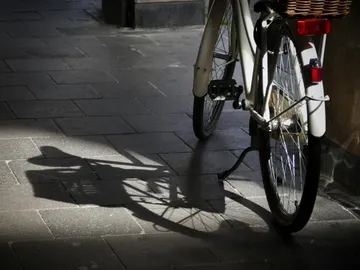 Ein Fahrrad steht auf einem Gehweg in der Sonne.