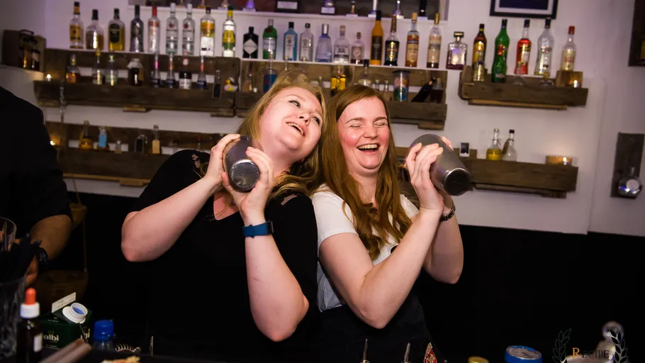 Zwei Frauen schütteln Cocktailmixer in einer Bar.