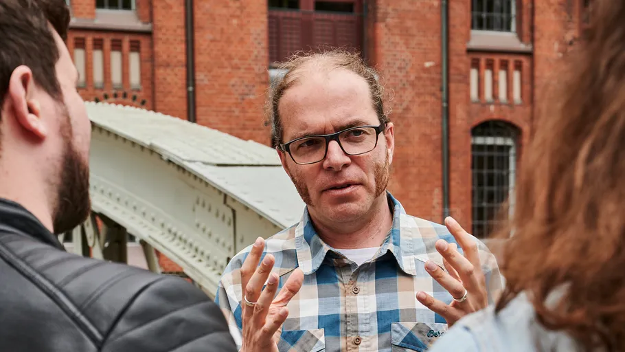 Man gesturing while talking outside brick building.