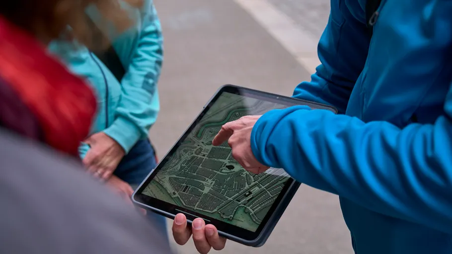 Person zeigt auf Tablet mit Stadtkarte.