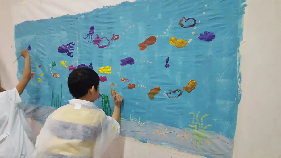 Kinder malen Unterwasserszene an der Wand.