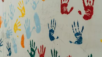 Colorful handprints painted on a wall.