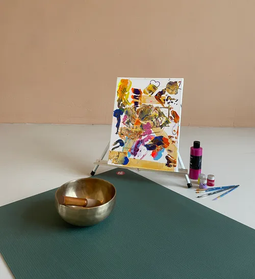 Singing bowl and colorful art painting on floor.