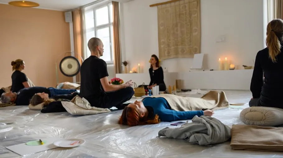 Menschen meditieren in Kerzenlicht auf weißen Matten.