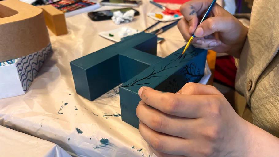 Person painting blue letter indoors.
