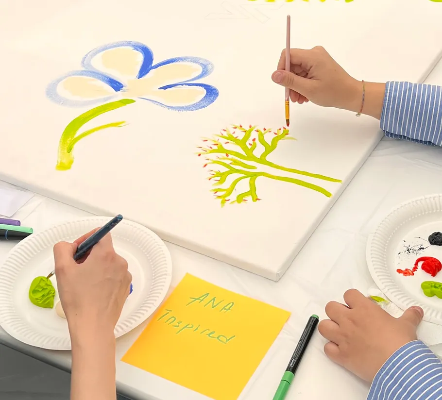 People painting flowers on a large canvas.