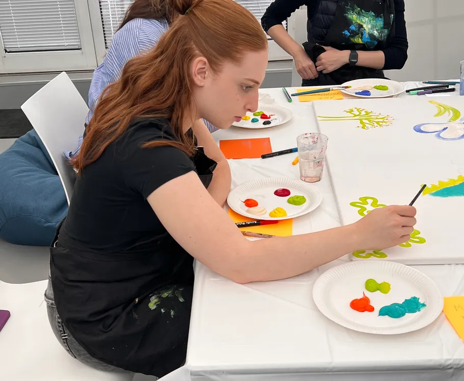 Woman painting colorful design on canvas indoors.