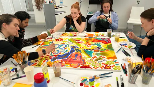 Gruppe malt lebendiges Wandbild im Studio.