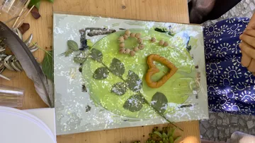 Blattkunst auf Tisch mit Händen in der Nähe.