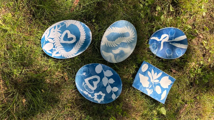 Blaue Keramikteller mit weißen Pflanzenmustern auf Gras.