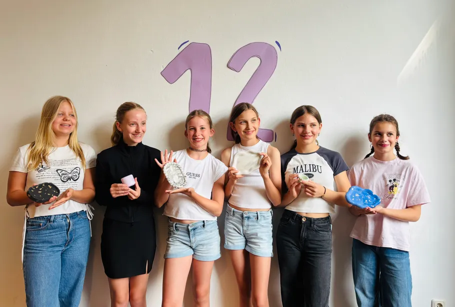Six young people holding soap in front of wall.